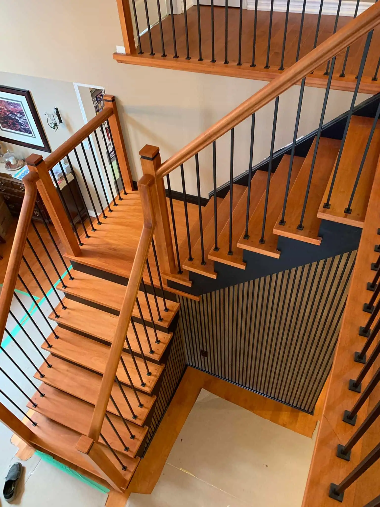 High-angle view of a custom interior staircase with hardwood treads, black metal balusters, and a modern vertical wood slat accent wall