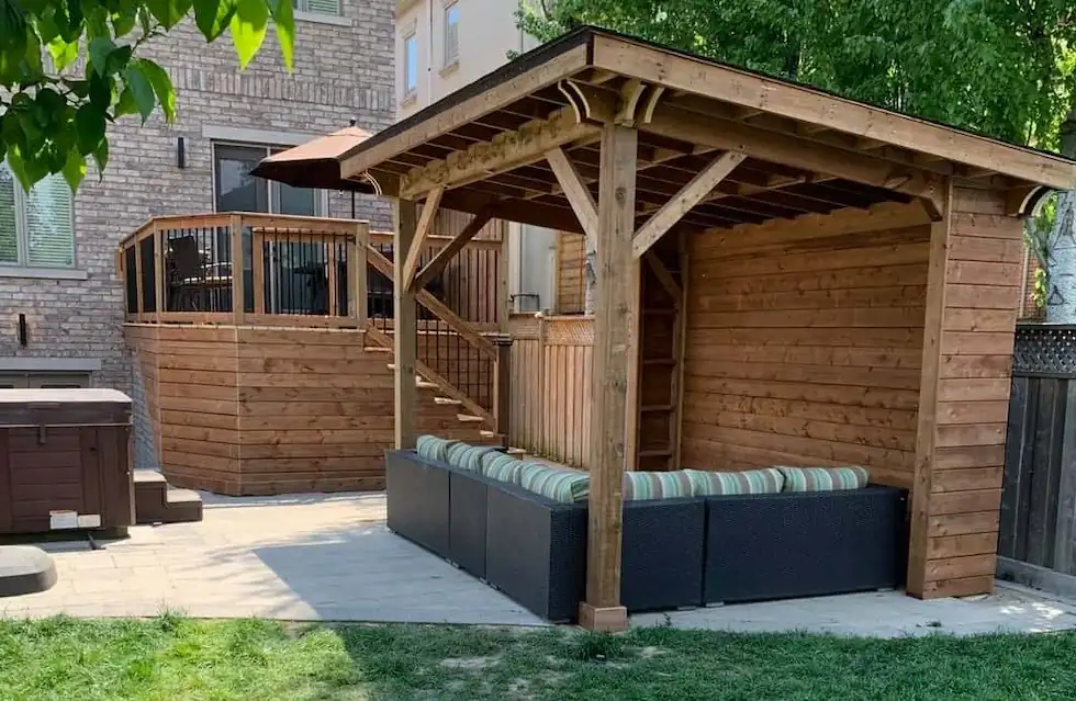 Custom heavy-timber wooden gazebo providing a covered outdoor lounge area, situated next to a raised deck and hot tub